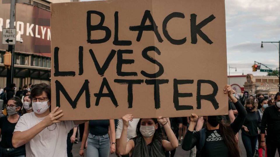 Manifestantes erguendo o cartaz com a frase Black lives Matter