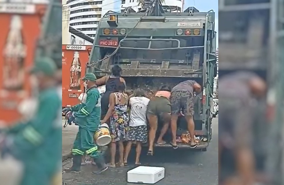 Pessoas buscam comida descartada em caminhão de lixo, em Fortaleza